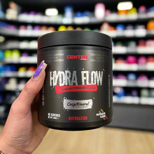 Close-up of (Conteh Sports Hydra Flow Daily Hydration Formula 300g) held up inside My Supplement Shop, clearly showing the front label in a Sports Nutrition setting.